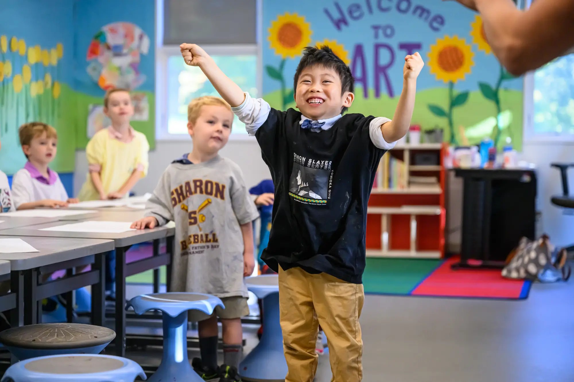 授業中に両手を上げて喜ぶ少年